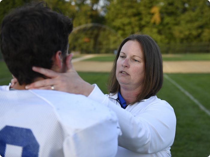 Exeter Trainer inspects football player for concussion